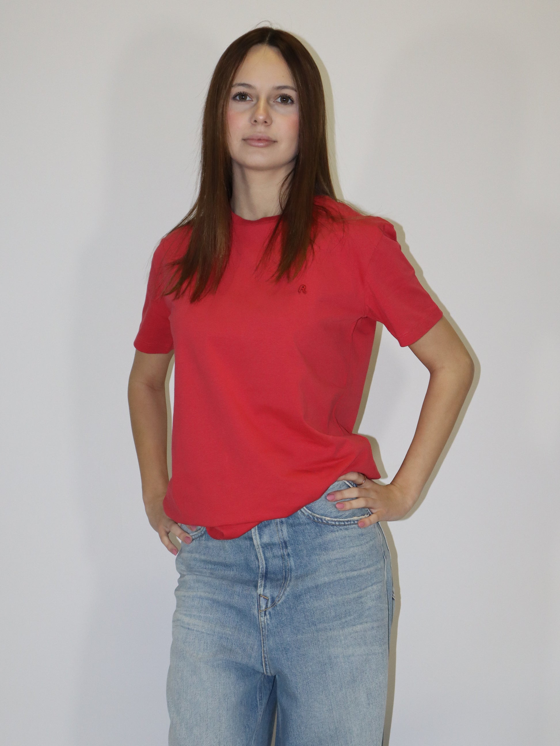 Dámské červené tričko Replay s krátkým rukávem a malým červeným logem, světlé volné džíny, postava proti bílému pozadí.