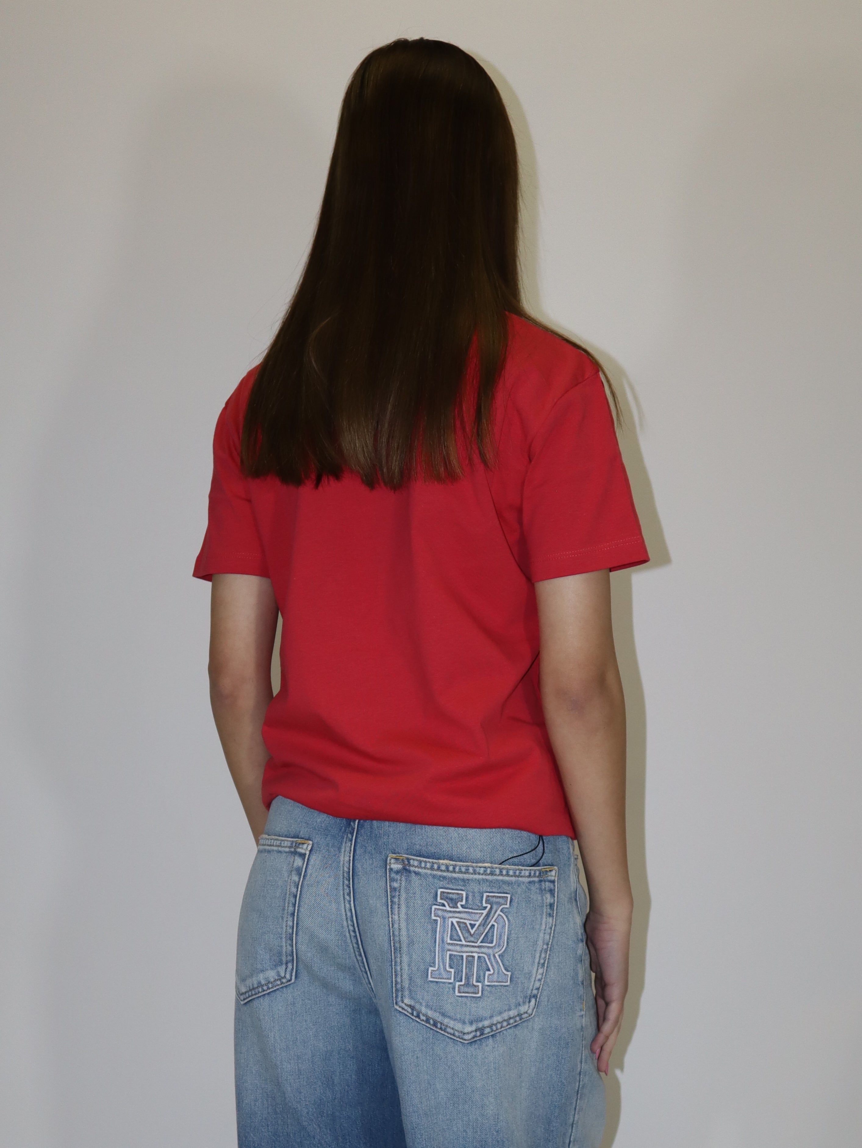 Dámské červené tričko Replay s krátkým rukávem a malým červeným logem, světlé volné džíny, postava proti bílému pozadí.